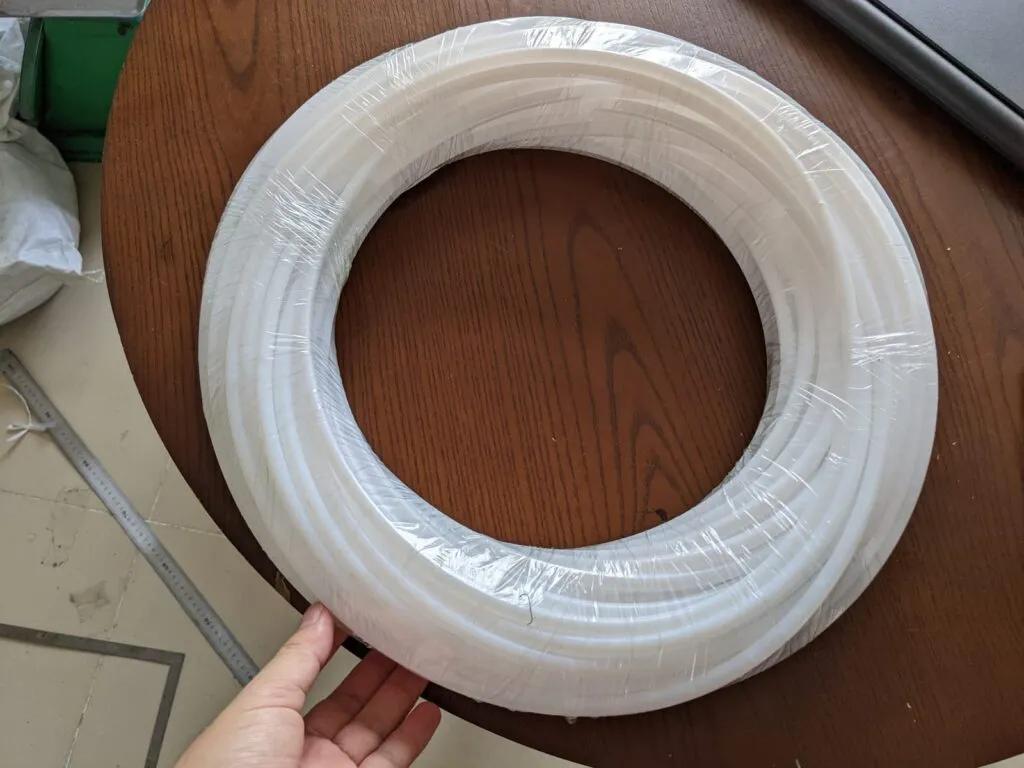 Cuộn ống PTFE trắng đặt trên mặt bàn gỗ