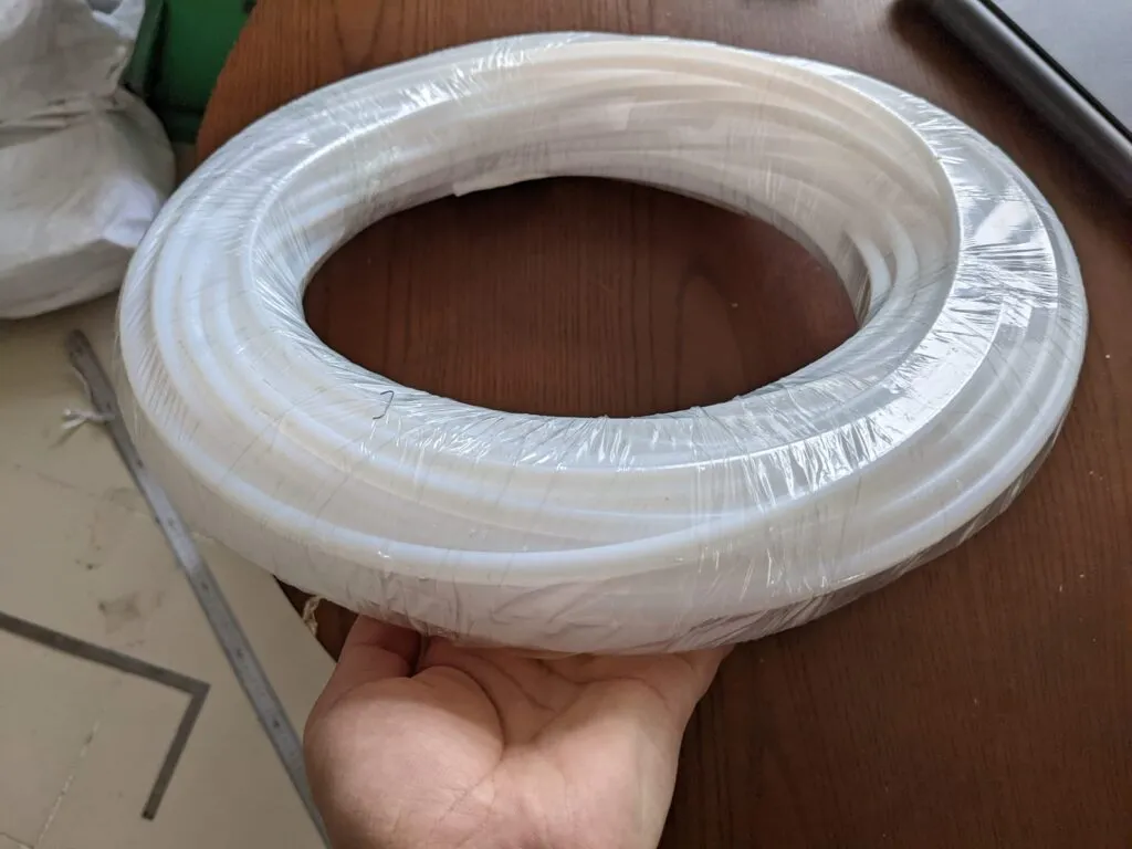 Cuộn ống teflon trắng bọc màng co đặt trên tay