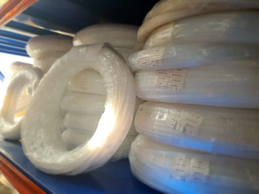 Cuộn ống teflon trắng giữa chồng hàng trên kệ