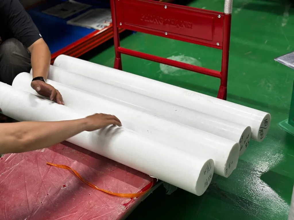Hai người đỡ cây teflon phi lớn trên bàn
