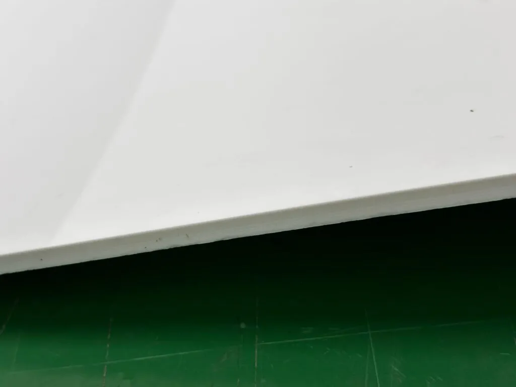 Mép tấm teflon dày nằm trên sàn xanh