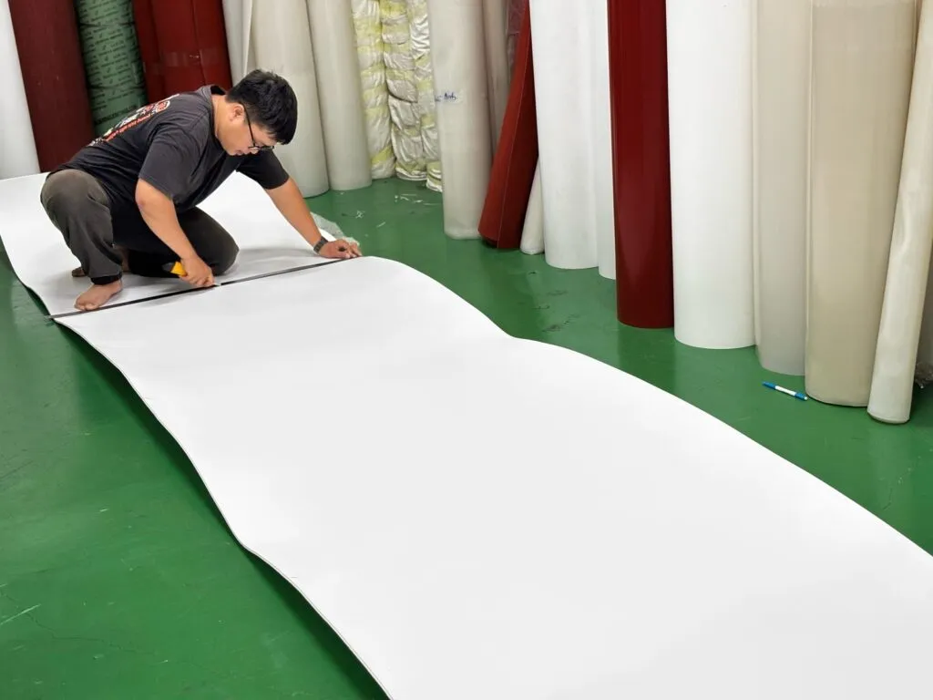 Thợ kho trải tấm teflon ra sàn để cắt